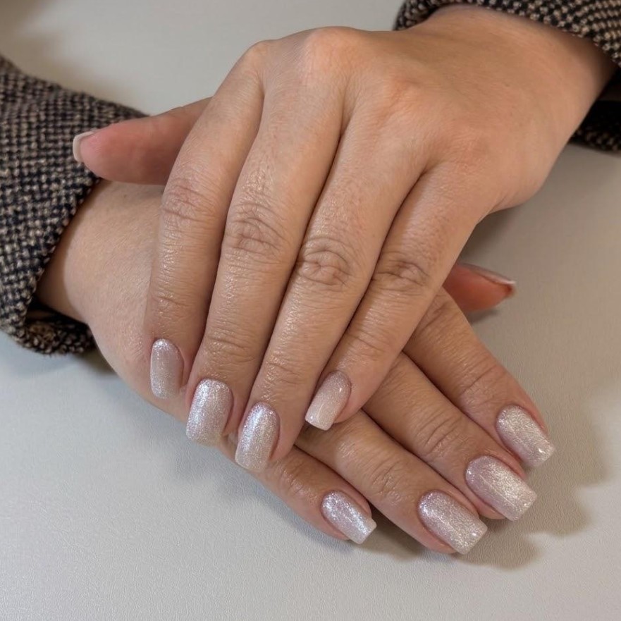 Mãos com unhas em formato quadrado suave e esmalte perolado com brilho, manicure feita no Nix Beauty Salon, no Shopping Palladium, em Curitiba
