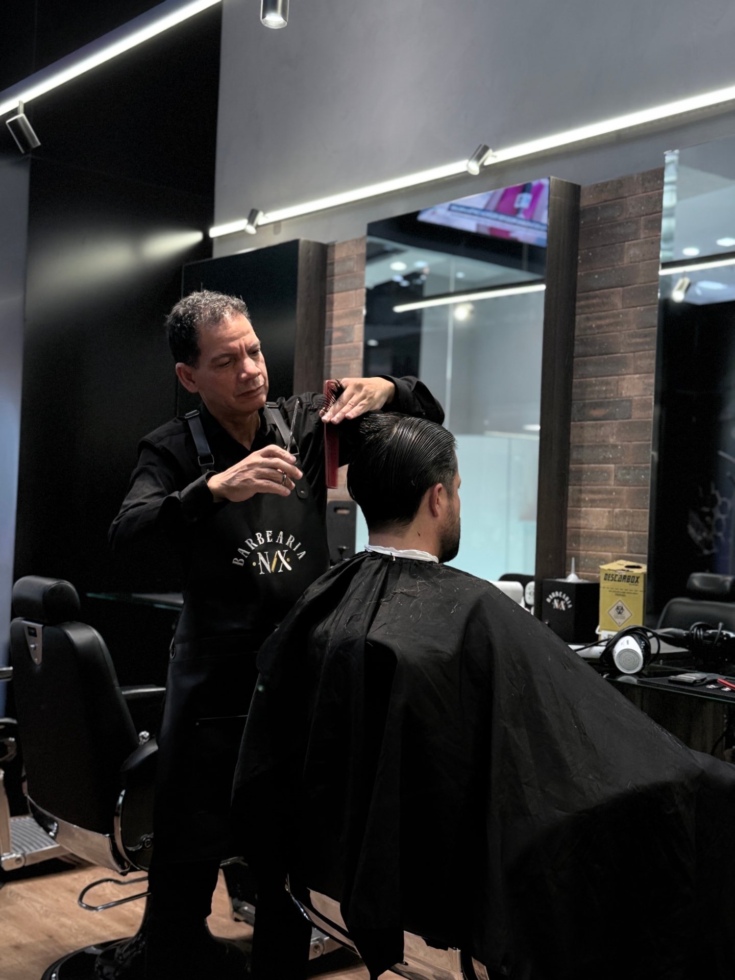 Cliente recebendo corte de cabelo na Nix Barbearia, no Shopping Palladium, em Curitiba