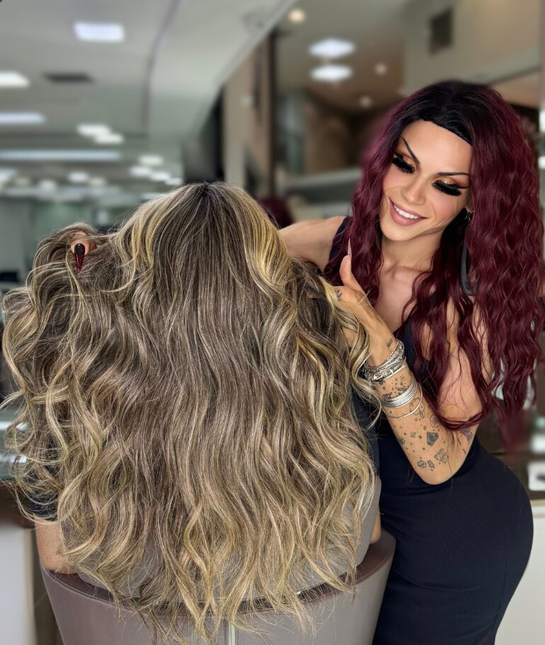 Profissional do Nix Beauty Salon finalizando cabelo ondulado com mechas loiras em cliente, no Shopping Palladium, em Curitiba