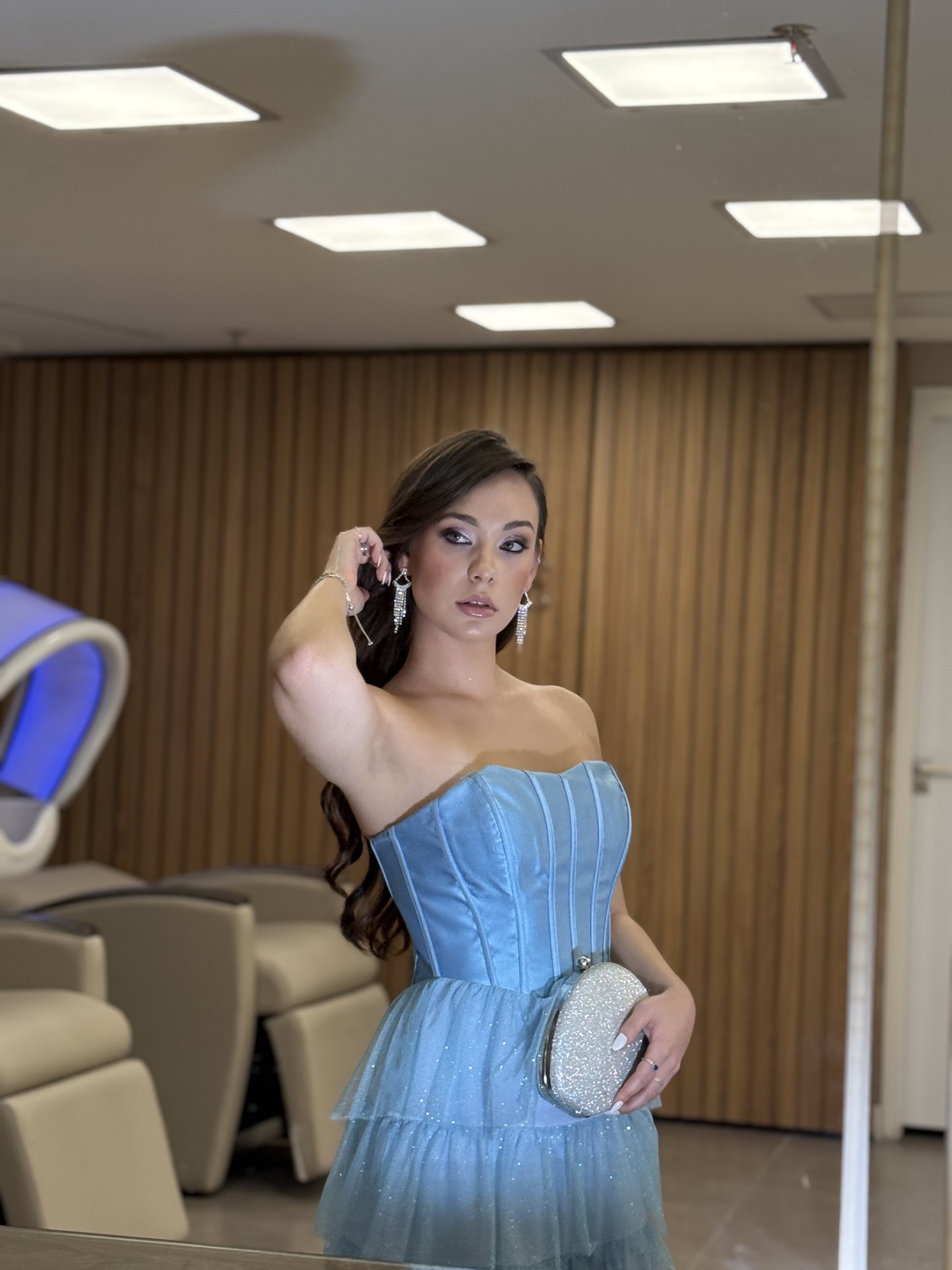 Cliente com cabelo castanho ondulado em penteado meio preso, maquiagem glamourosa e vestido azul claro com saia de tule, produção para festa do Nix Beauty Salon, no Shopping Palladium, em Curitiba
